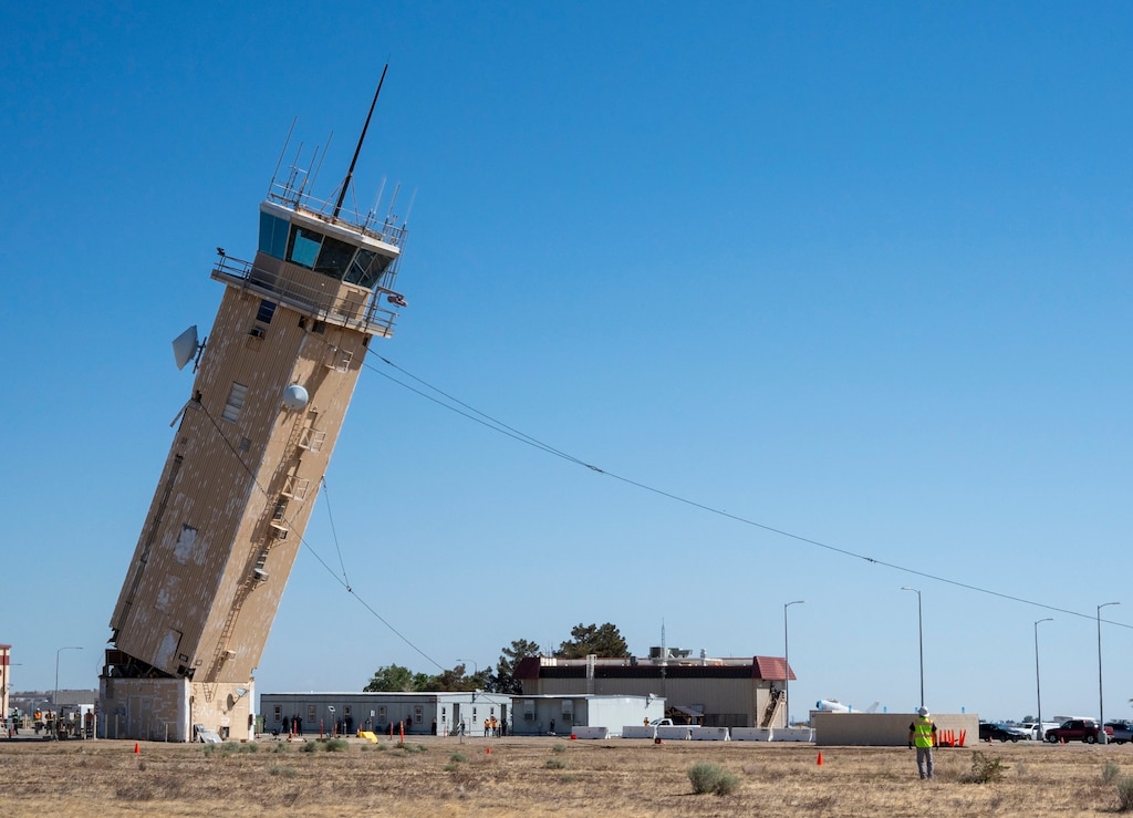 A decommissioned air traffic control tower at Plant 42 falls April 29 during its demolition at the Air Force installation in Palmdale, California. Crews used an excavator and cable system to safely bring down the structure, which had its support beams cut in advance.