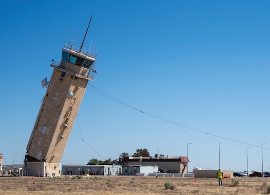 A decommissioned air traffic control tower at Plant 42 falls April 29 during its demolition at the Air Force installation in Palmdale, California. Crews used an excavator and cable system to safely bring down the structure, which had its support beams cut in advance.