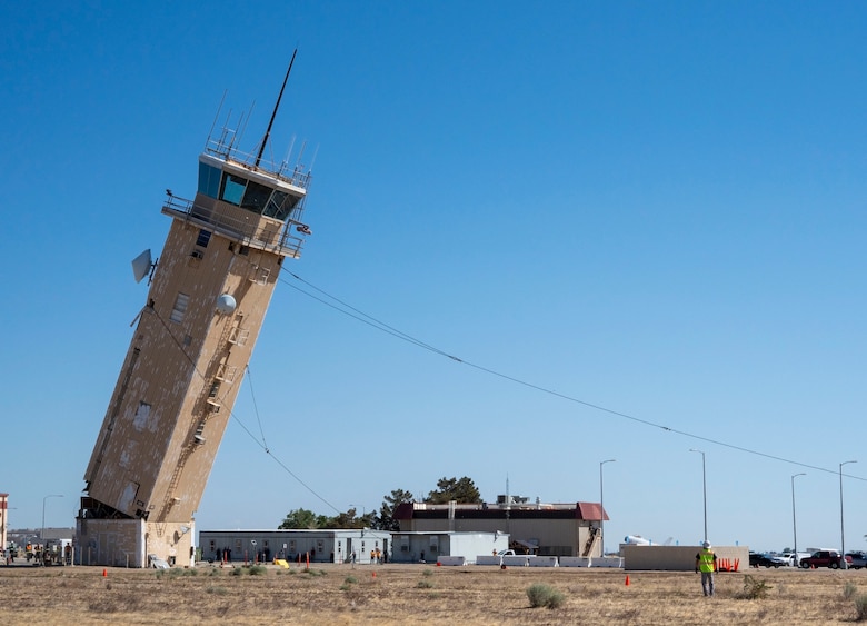 A decommissioned air traffic control tower at Plant 42 falls April 29 during its demolition at the Air Force installation in Palmdale, California. Crews used an excavator and cable system to safely bring down the structure, which had its support beams cut in advance.