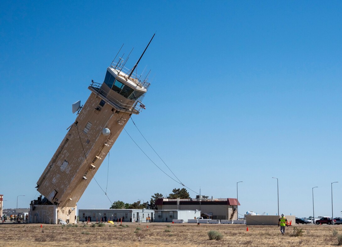 A decommissioned air traffic control tower at Plant 42 falls April 29 during its demolition at the Air Force installation in Palmdale, California. Crews used an excavator and cable system to safely bring down the structure, which had its support beams cut in advance.