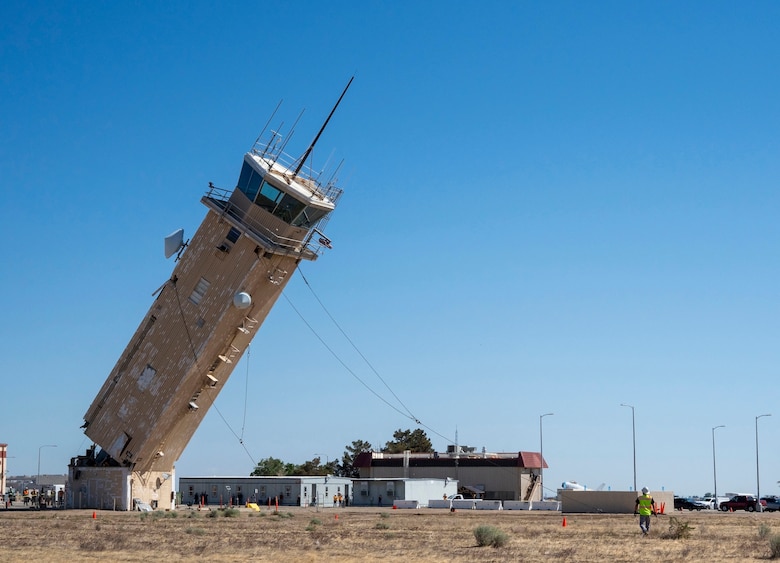 A decommissioned air traffic control tower at Plant 42 falls April 29 during its demolition at the Air Force installation in Palmdale, California. Crews used an excavator and cable system to safely bring down the structure, which had its support beams cut in advance.