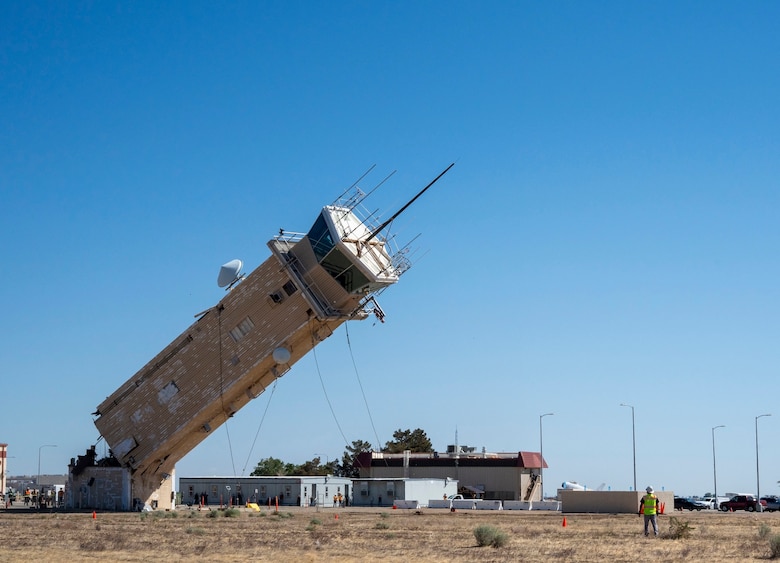 A decommissioned air traffic control tower at Plant 42 falls April 29 during its demolition at the Air Force installation in Palmdale, California. Crews used an excavator and cable system to safely bring down the structure, which had its support beams cut in advance.