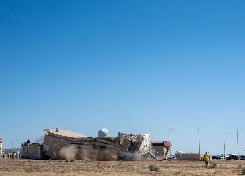 A decommissioned air traffic control tower at Plant 42 falls April 29 during its demolition at the Air Force installation in Palmdale, California. Crews used an excavator and cable system to safely bring down the structure, which had its support beams cut in advance.