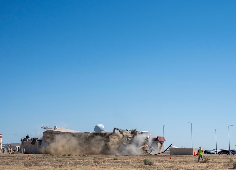 A decommissioned air traffic control tower at Plant 42 falls April 29 during its demolition at the Air Force installation in Palmdale, California. Crews used an excavator and cable system to safely bring down the structure, which had its support beams cut in advance.