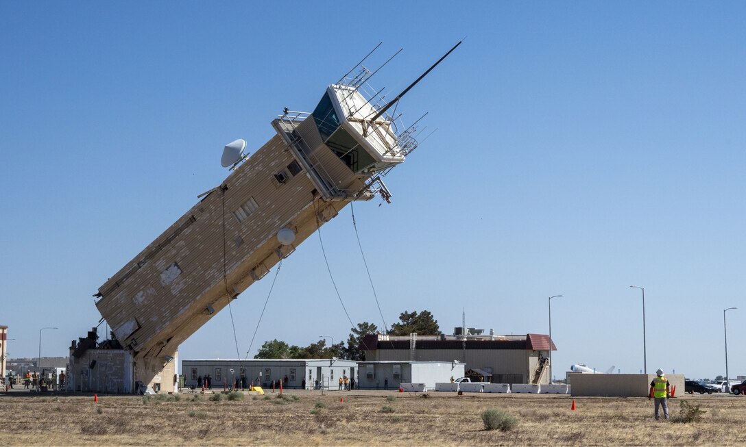A decommissioned air traffic control tower at Plant 42 falls April 29 during its demolition at the Air Force installation in Palmdale, California. Crews used an excavator and cable system to safely bring down the structure, which had its support beams cut in advance.
