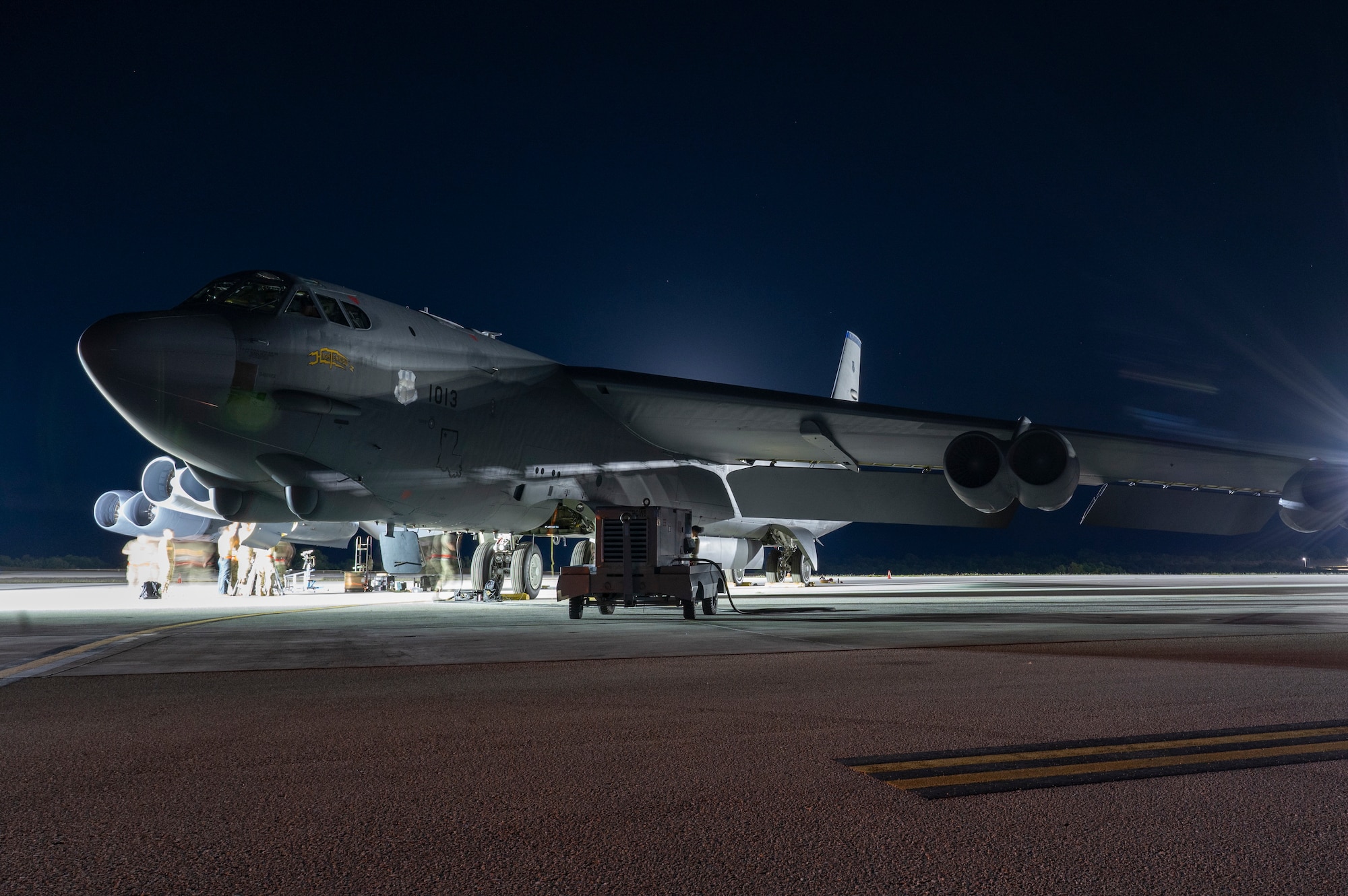 A very large military aircraft sits on a tarmac surrounded by equipment