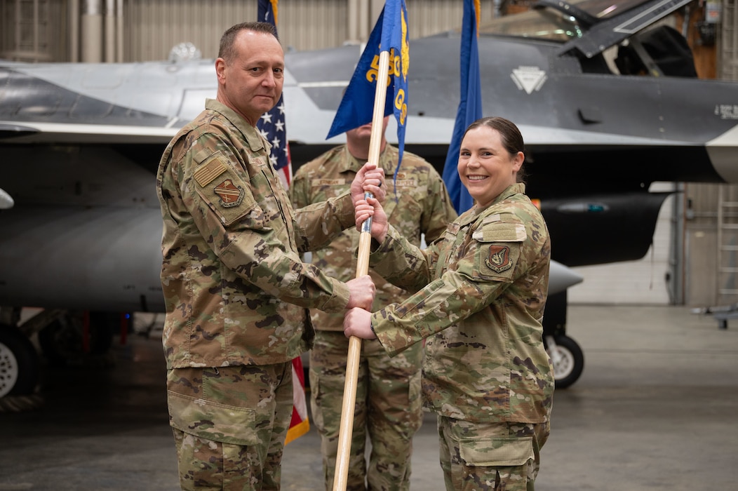 U.S. Air Force Lt. Col. Jerry Copeland, 354th Maintenance Group commander, passes the guidon to Maj. Renee Bohac, 18th Fighter Generation Squadron incoming commander, during a change of command ceremony at Eielson Air Force Base, Alaska, May 30, 2025.