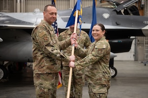 U.S. Air Force Lt. Col. Jerry Copeland, 354th Maintenance Group commander, passes the guidon to Maj. Renee Bohac, 18th Fighter Generation Squadron incoming commander, during a change of command ceremony at Eielson Air Force Base, Alaska, May 30, 2025.
