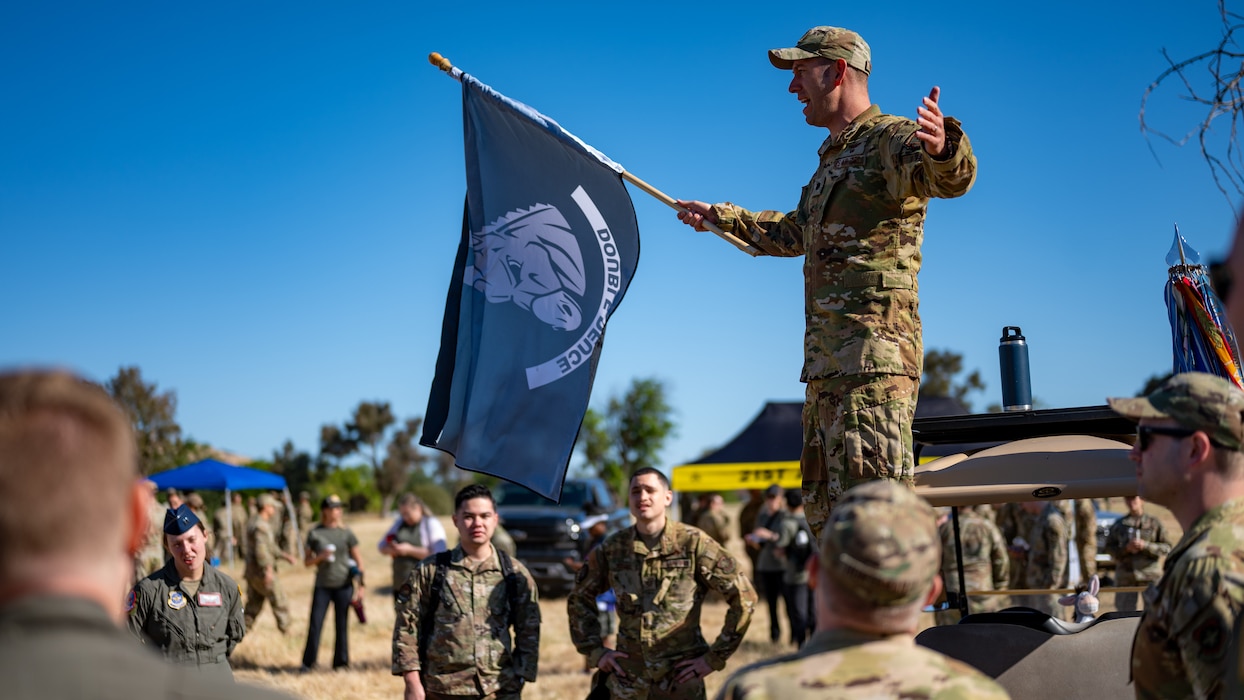 An Airman gives a speech with a flag