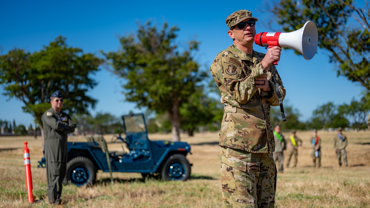 Col. Johnson speaks through a megaphone with a jeep in the foreground