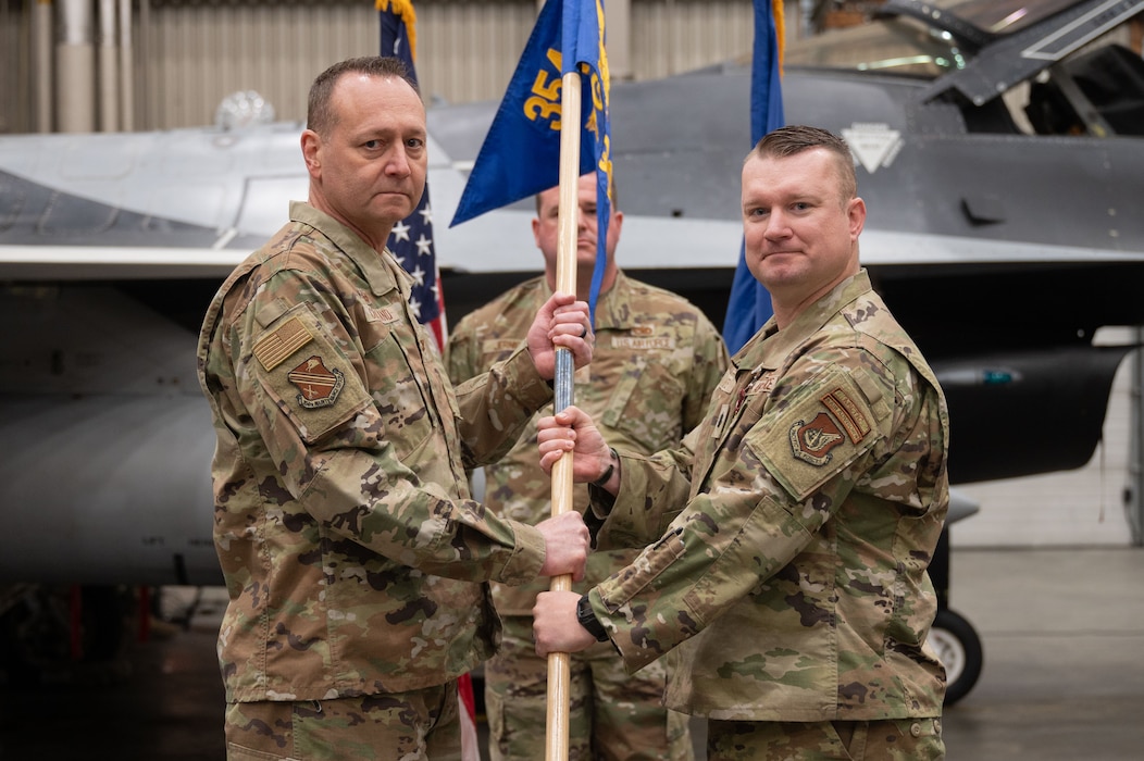 U.S. Air Force Lt. Col. Stephan White, right, 18th Fighter Generation Squadron outgoing commander, relinquishes the guidon to Col. Jerry Copeland, 354th Maintenance Group commander, during a change of command ceremony at Eielson Air Force Base, Alaska, May 30, 2025.