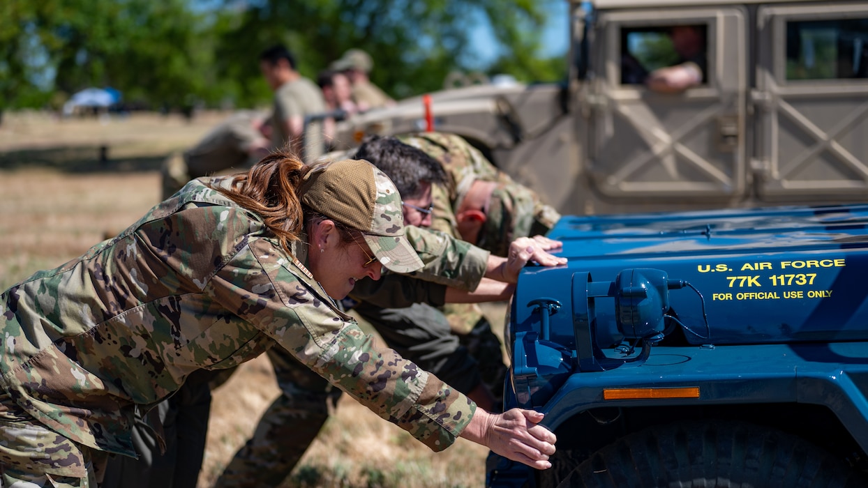 Airmen push a jeep and Humvee