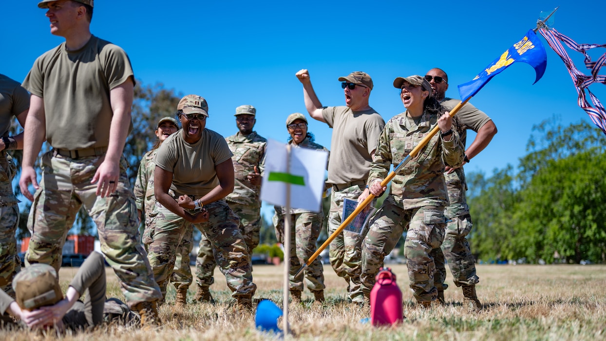 Airmen cheer for their fellow service members with a guidon