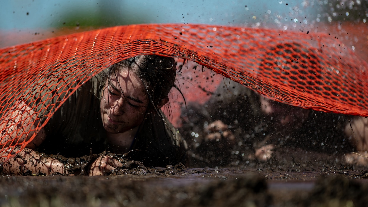 Airmen crawl through a mud pit