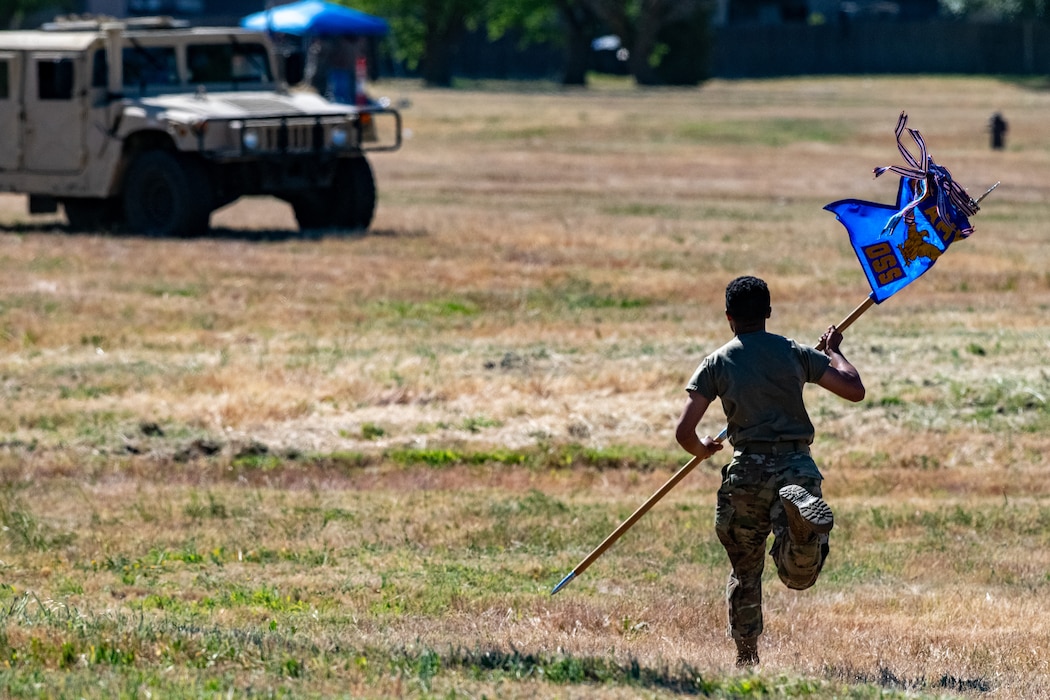 Airman runs toward Humvee with guidon