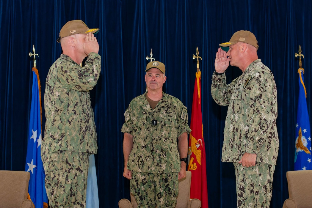 U.S. Navy Vice Adm. Scott Gray, commander, Navy Installations Command, center, officiates the turnover between Rear Adm. Brent DeVore, outgoing commander, Joint Region Marianas, right, and Rear Adm. Brett Mietus, incoming JRM commander, during a change of command ceremony at Guam High School, May 29.