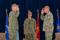 U.S. Navy Vice Adm. Scott Gray, commander, Navy Installations Command, center, officiates the turnover between Rear Adm. Brent DeVore, outgoing commander, Joint Region Marianas, right, and Rear Adm. Brett Mietus, incoming JRM commander, during a change of command ceremony at Guam High School, May 29.