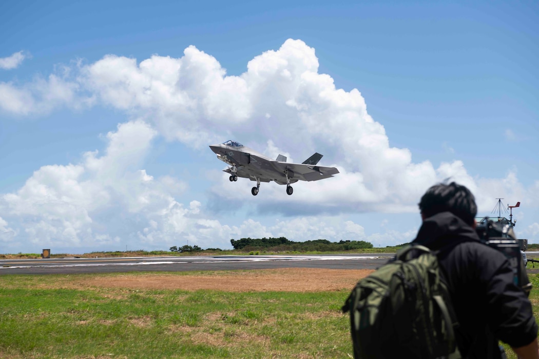 A Japanese media representative captures a U.S. Navy F-35C Lightning II, assigned to Strike Fighter Squadron (VFA) 147 and attached to Carrier Air Wing (CVW) 5, as the aircraft conducts a “touch-and-go” during a field carrier landing practice (FCLP) at Iwo To, Japan, May 25, 2025.