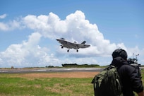 A Japanese media representative captures a U.S. Navy F-35C Lightning II, assigned to Strike Fighter Squadron (VFA) 147 and attached to Carrier Air Wing (CVW) 5, as the aircraft conducts a “touch-and-go” during a field carrier landing practice (FCLP) at Iwo To, Japan, May 25, 2025.
