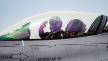 pilot inside a cockpit salutes towards out of frame person