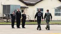 team members salute a pilot walking with another team member