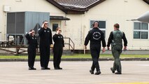 team members salute a pilot walking with another team member