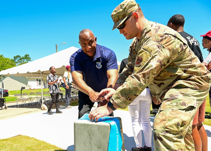 Anthony Hern, left, Senior Non-commissioned Officer Academy student registrar, and U.S. Air Force Tech. Sgt. Thomas Harvey, 42nd Contracting Squadron non-commissioned officer in charge of the defense education flight, sign a ribbon in Montgomery, Alabama, May 20, 2025.