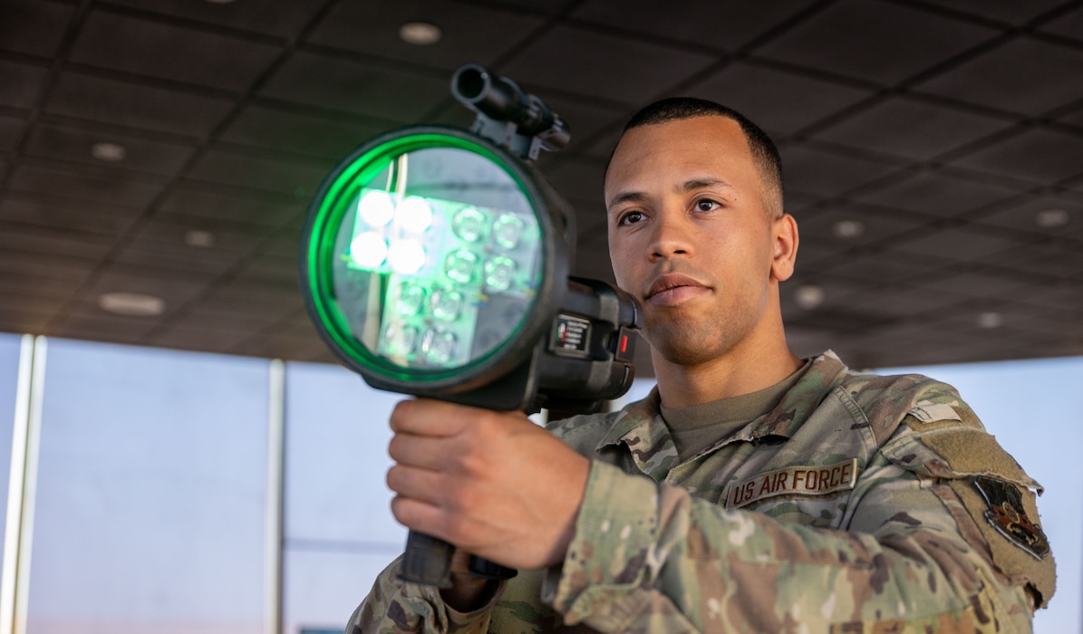 A man hold a light gun that is shining a green color.