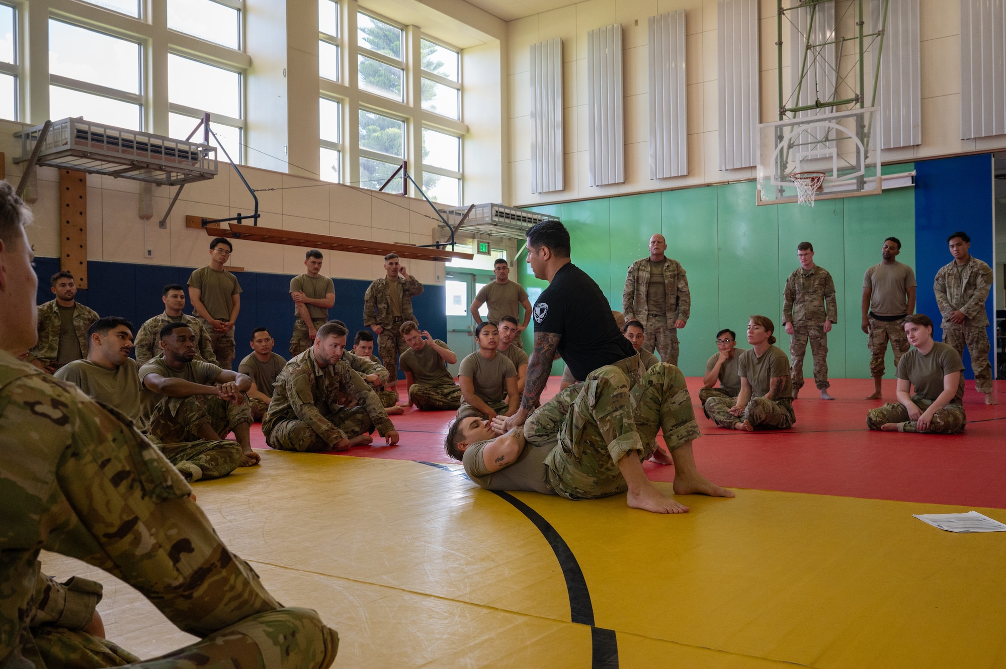 instructors demonstrate moves while students watch during a combatives course