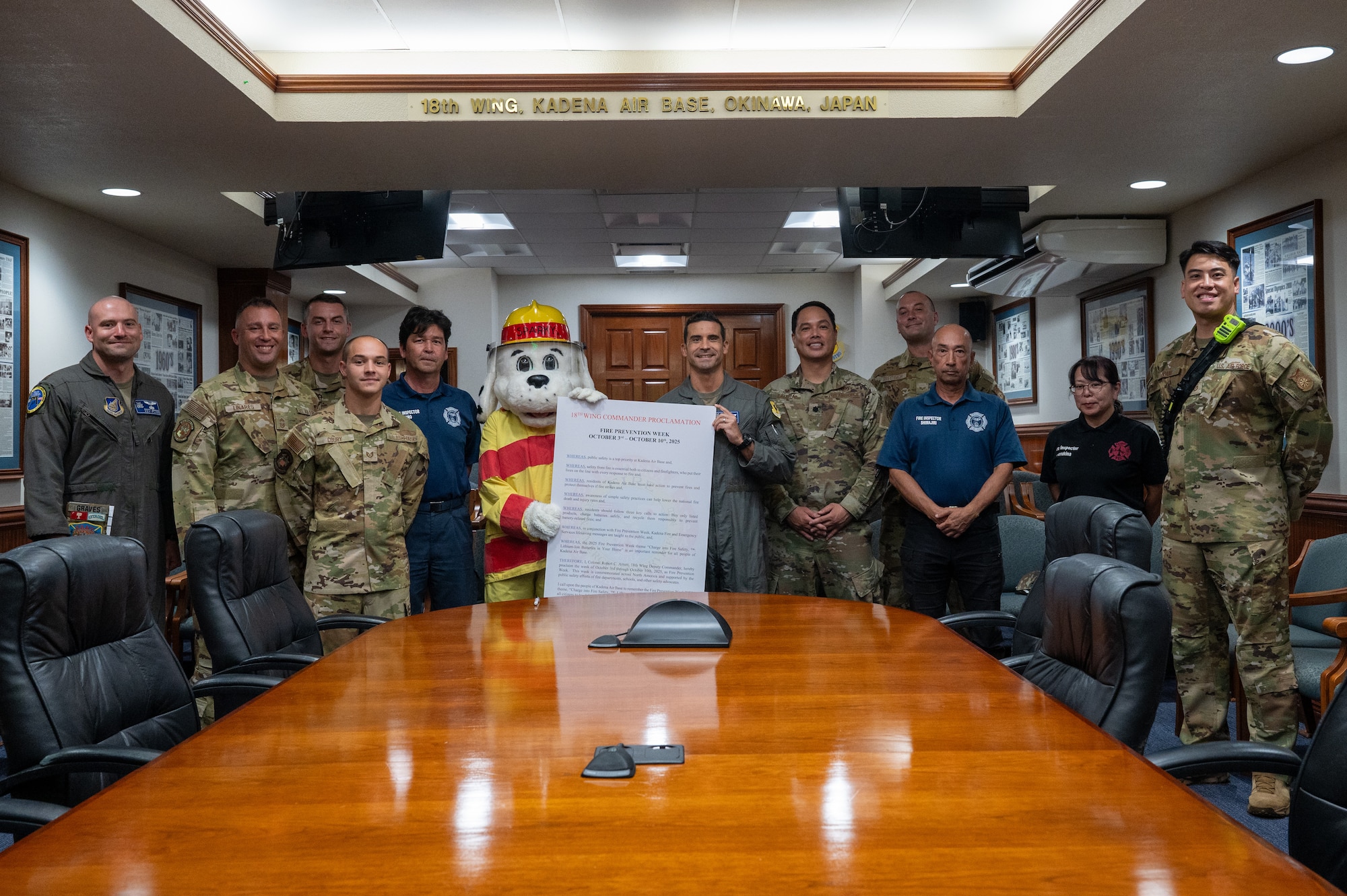 U.S. Air Force Col. Robert Arnett, 18th Wing deputy commander, and members from the 18th Civil Engineer Group pose for a photo in front of the 2025 Fire Prevention proclamation.
