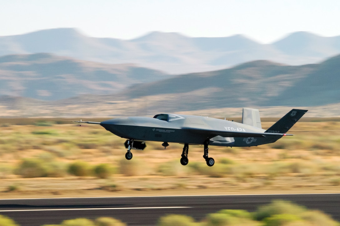 A small aircraft takes off from a flight line with mountains in the distance.