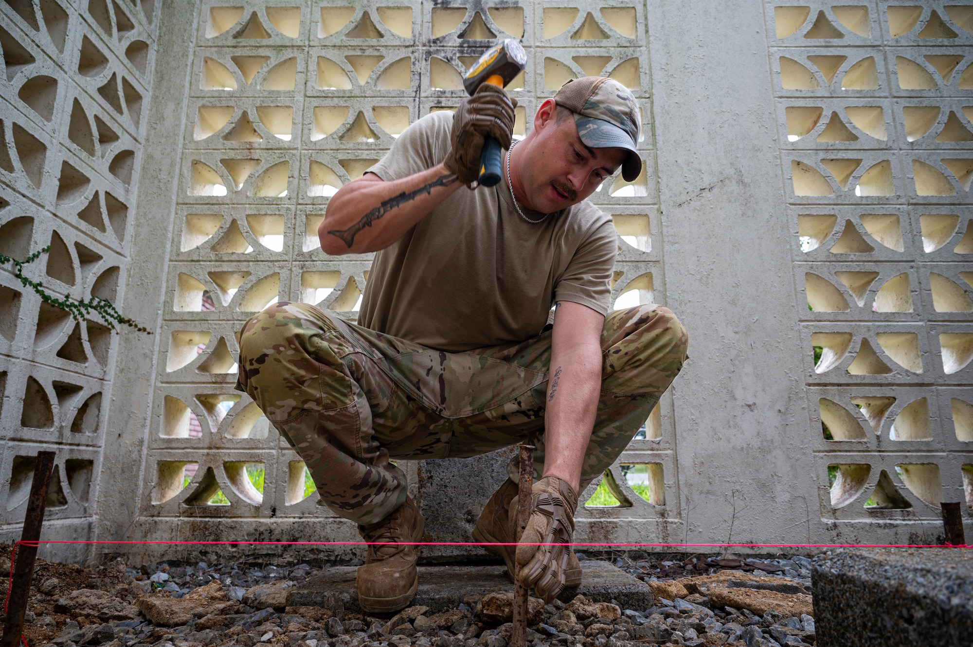 U.S. Air Force Senior Airman Tristan Smedley, 11th Combat Air Base Squadron pavement and heavy equipment specialist, hammers a spike into the ground at Kadena Air Base, Japan, Oct. 27, 2025. The 11th CABS provides vital installation support to ensure base facilities remain safe and mission-ready. (U.S. Air Force photo by Airman Nathaniel Jackson)
