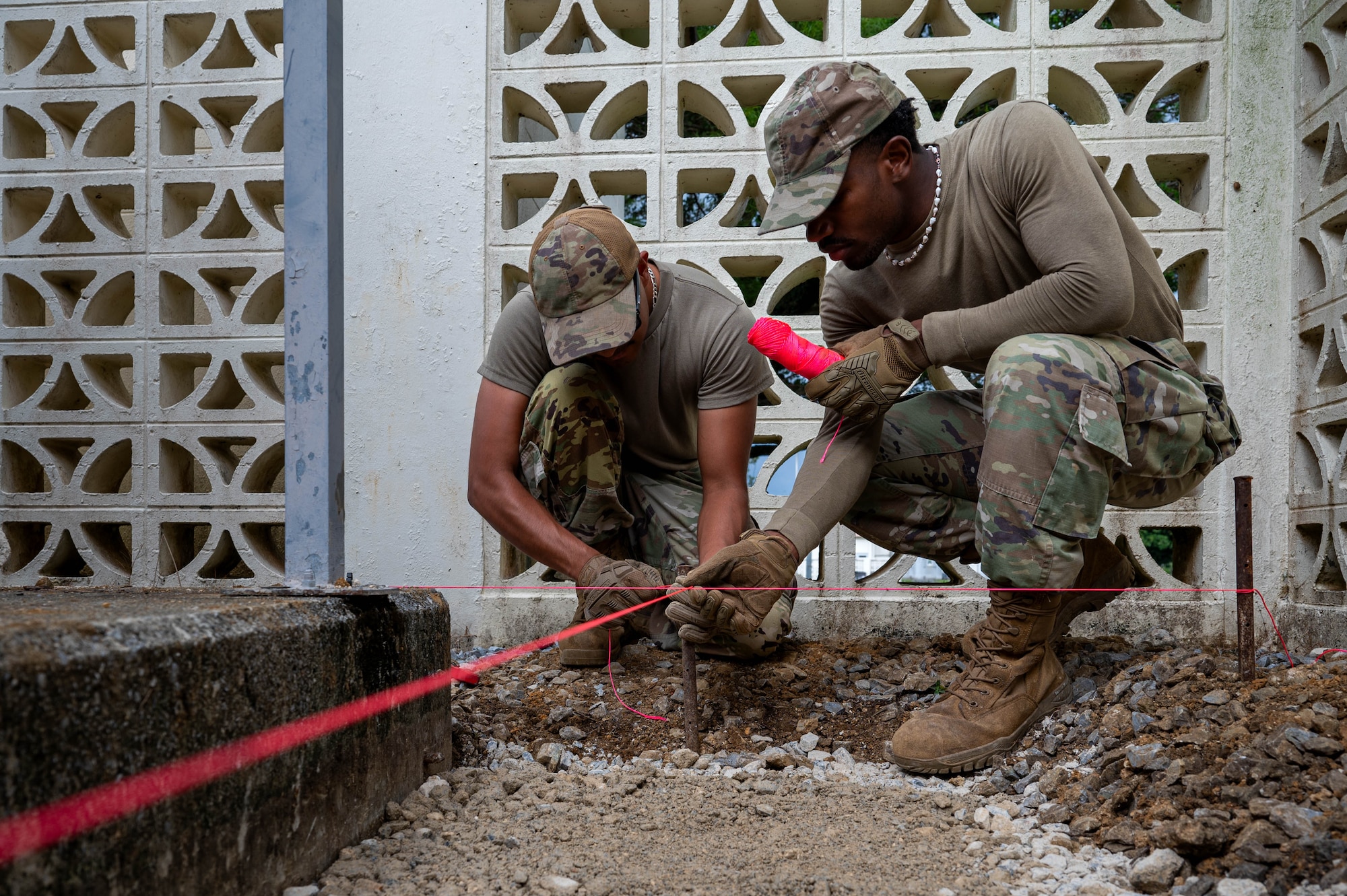 U.S. Air Force Senior Airman Eriberto Banuelas, left, 11th Combat Air Base Squadron heating, ventilation, and air conditioning technician and Senior Airman Sukari Holloway, 11th CABS electrical systems technician, level the ground to install a concrete base at Kadena Air Base, Japan, Oct. 27, 2025. The 11th CABS provides vital installation support to ensure base facilities remain safe and mission-ready. (U.S. Air Force photo by Airman Nathaniel Jackson)
