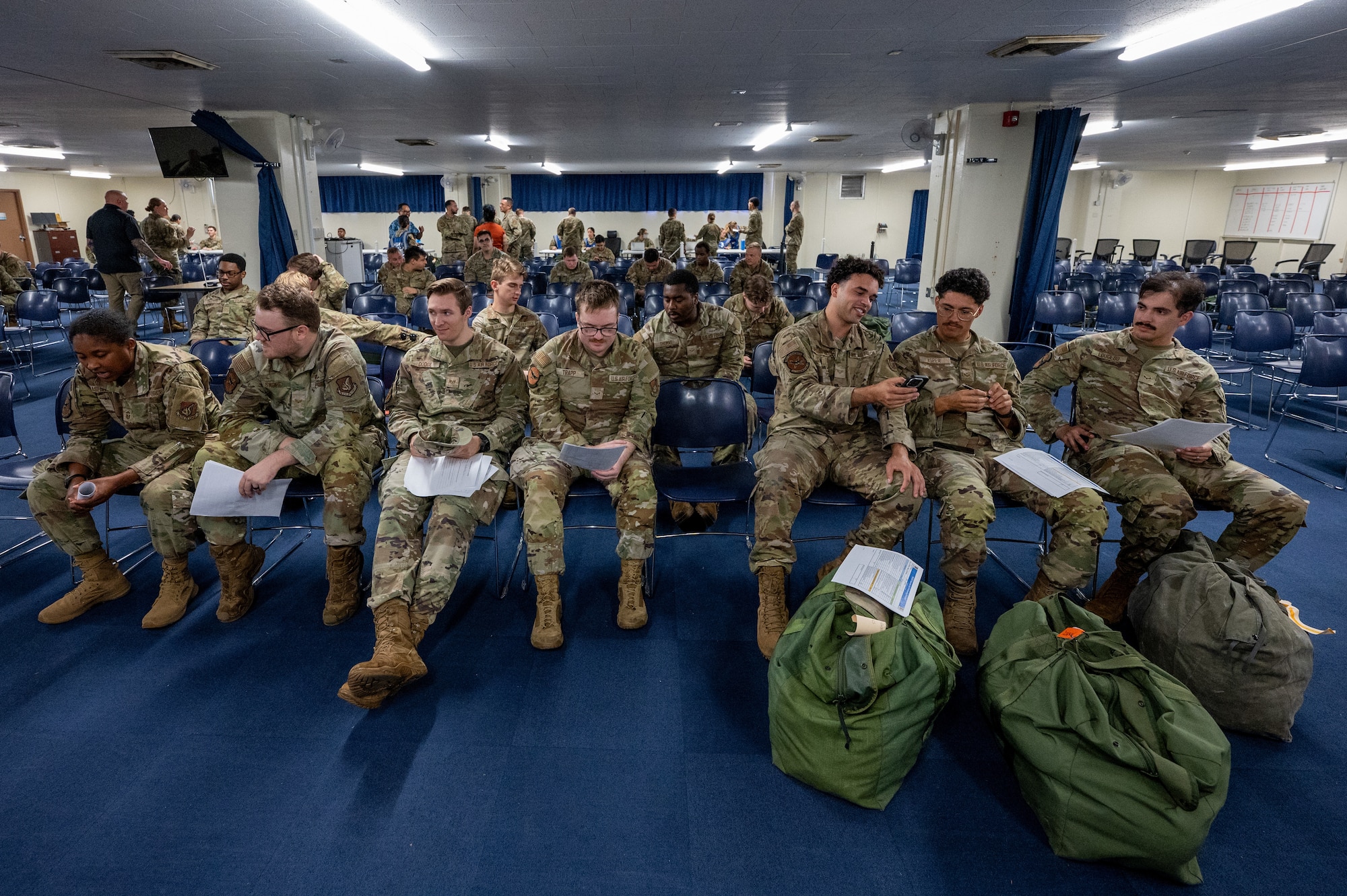 Service members sitting in a row with documents.