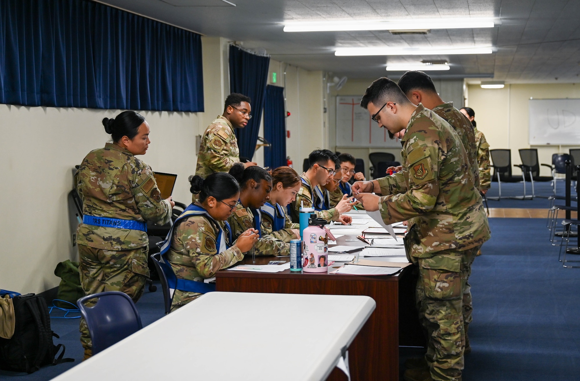 Service members look over documents in line.