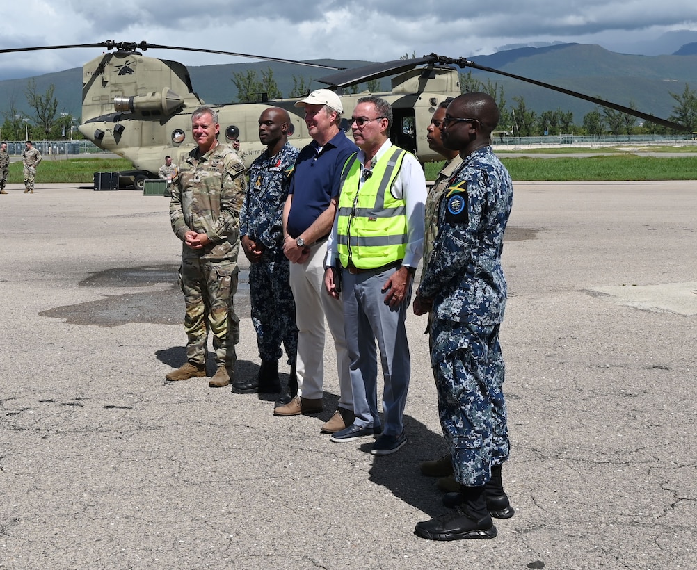 5 men stand in front of a military helicopter.