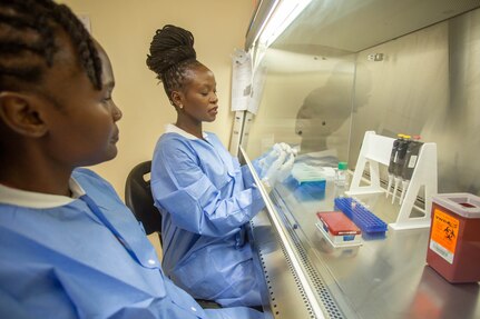 Researcher Esther Omuseni and graduate student Vane Kwamboka work with samples in the biosafety cabinet at the GEIS-affiliated AFI Basic Science Lab in Kisumu, Kenya. Thanks to enhancements installed to support their GEIS work, the lab amont of samples the lab is able to process daily has increased 10-fold. | Photo by Sarah Day Smith for HJFMRI