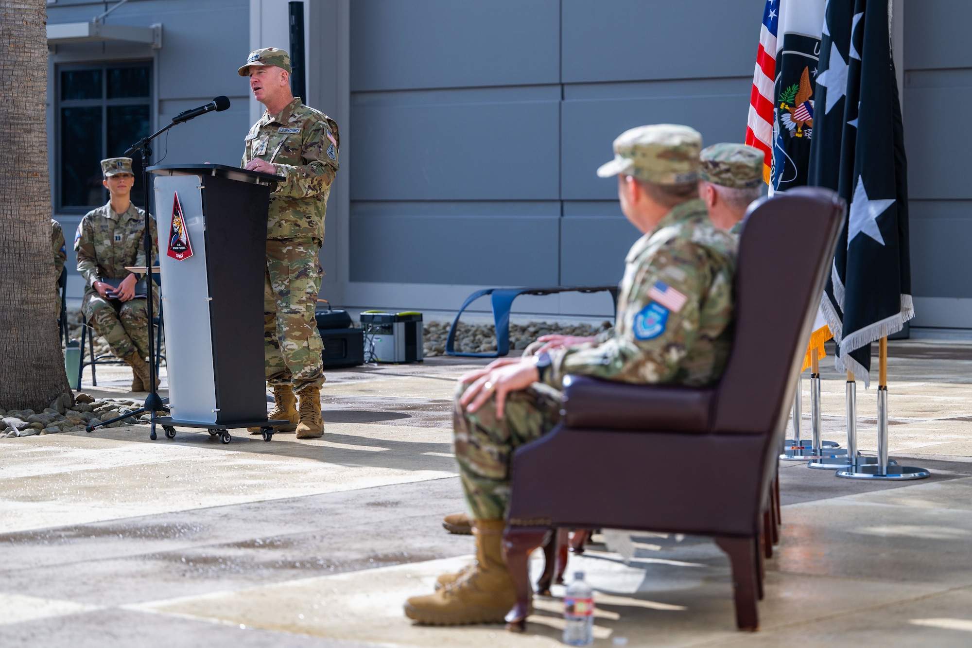 A military general speaks at a podium during a ceremony outside.