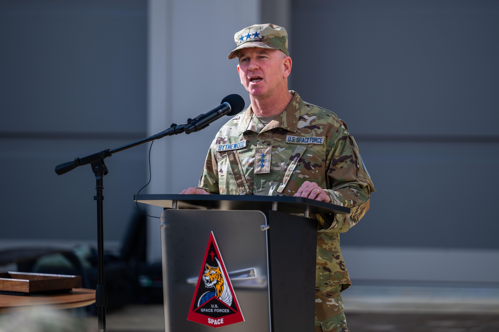 A military general talks at a podium outside