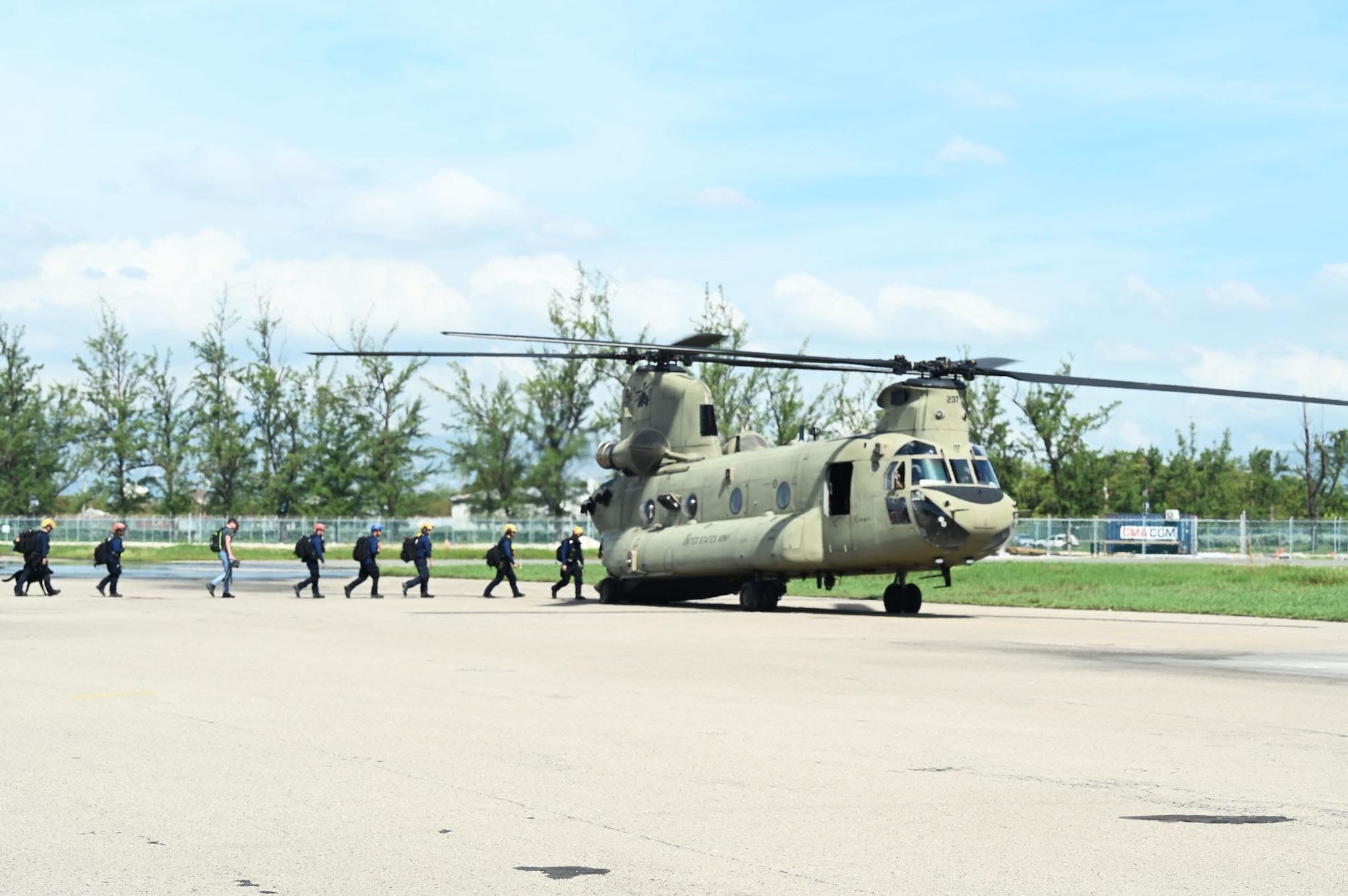 People walk into the back of a helicopter.