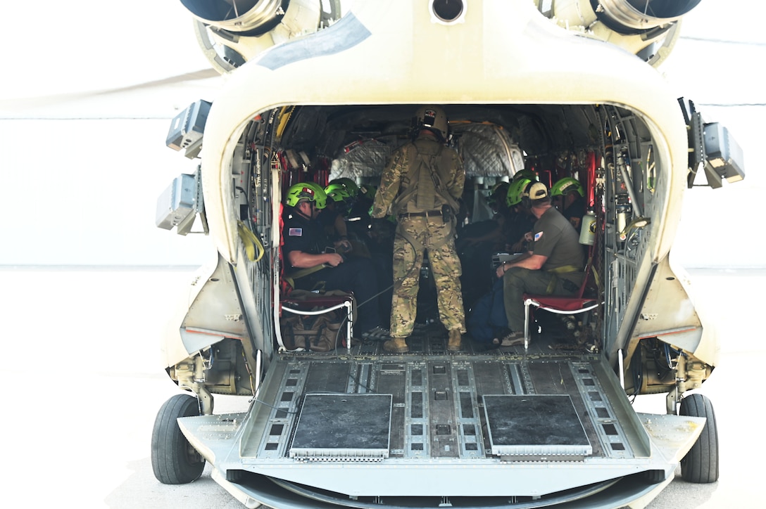 The back of a helicopter with a door down with people inside.