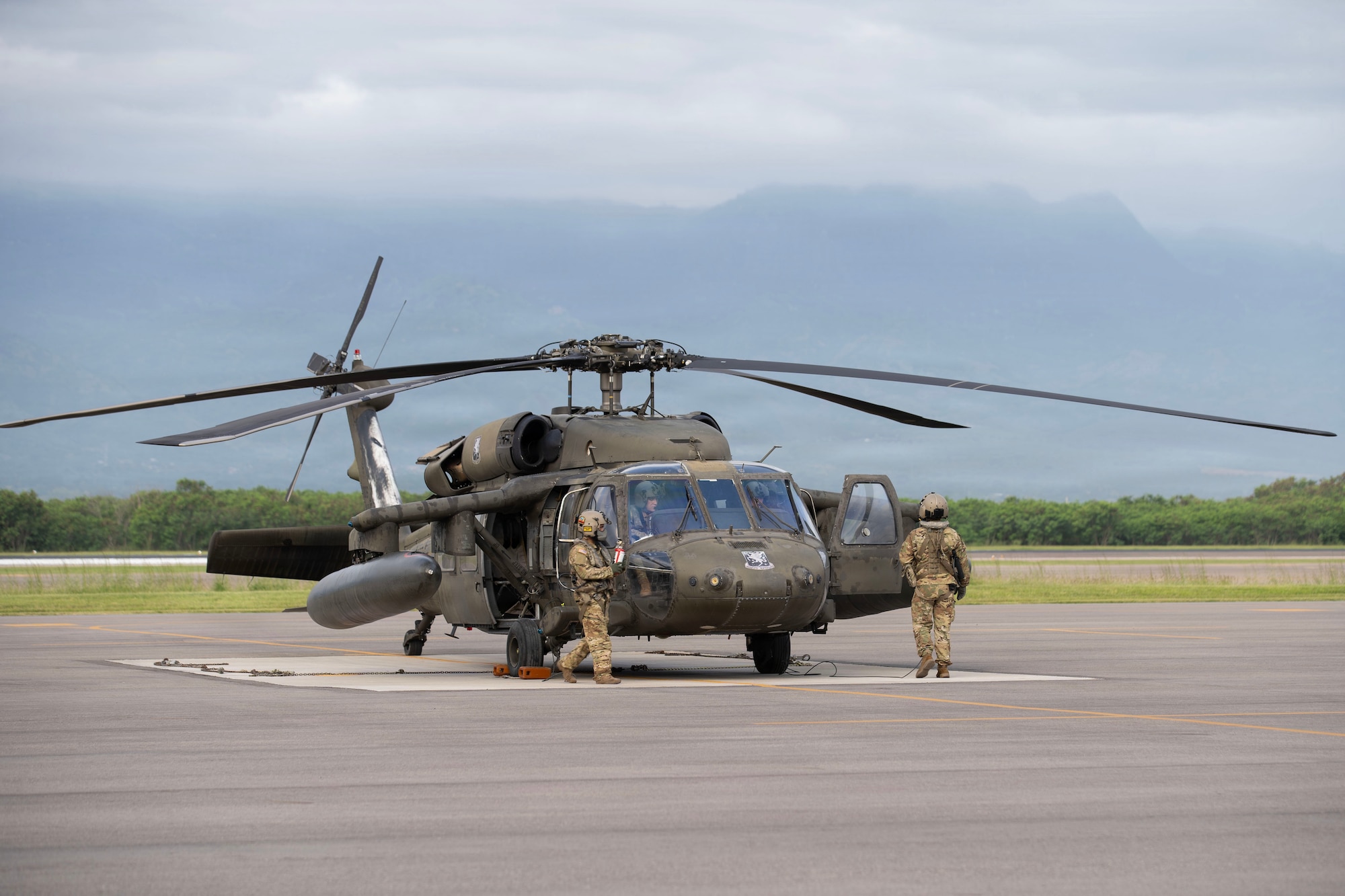 Military servicemembers stand in front of a helicopter
