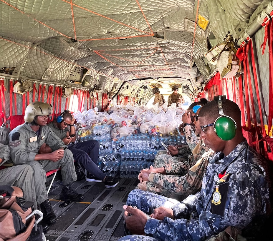 People in military uniforms sit in a helicopter.
