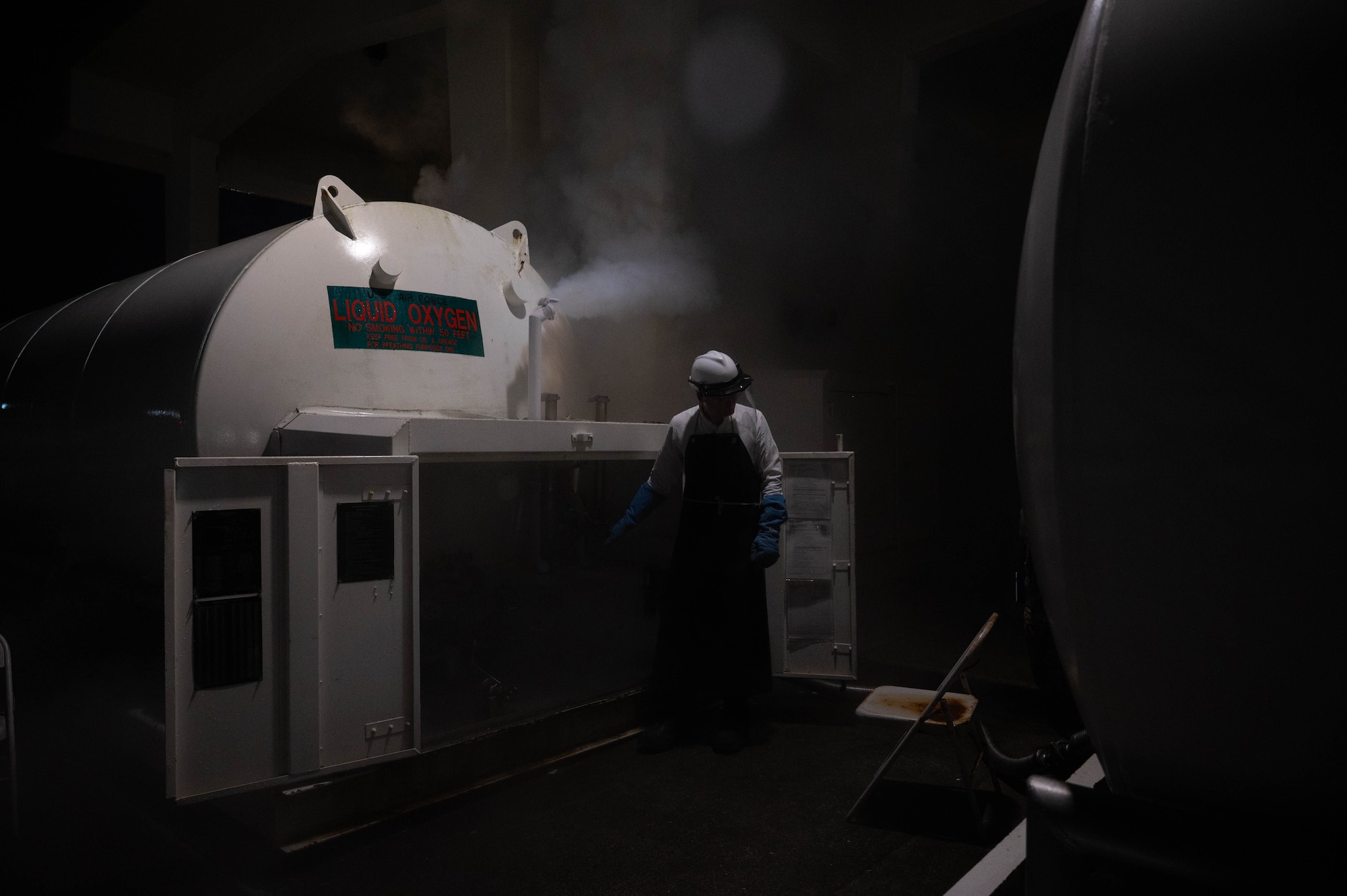 An airmen stands in the fog created by a standard oxygen tank pressure test.