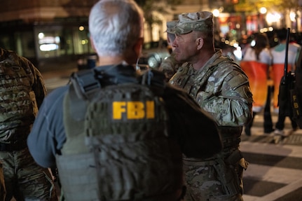 U.S. Army Command Sgt. Maj. Scott McKennon, right, Joint Task Force–District of Columbia senior enlisted leader, D.C. National Guard, coordinates with civilian law enforcement in Washington, D.C., Oct. 31, 2025. About 2,400 National Guard members support the D.C. Safe and Beautiful mission, assisting the Metropolitan Police Department in maintaining public safety for residents, commuters and visitors throughout the District.
