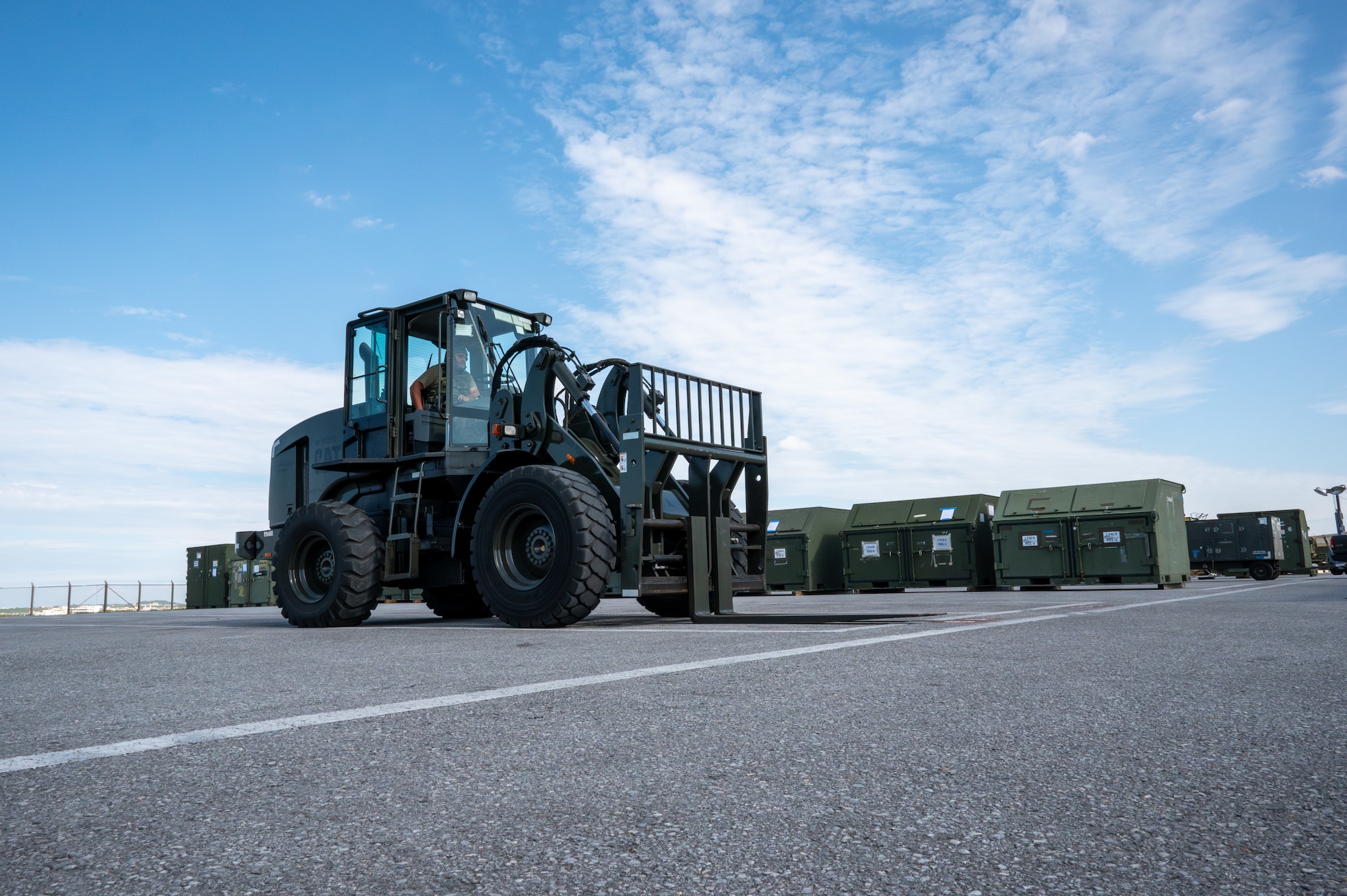 A service member drives a forklift.