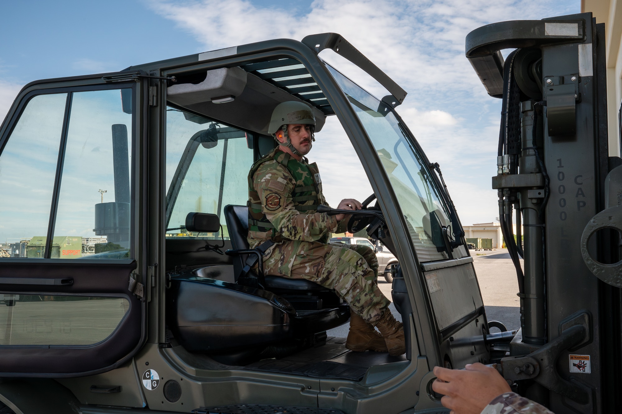 A service member drives a fork lift.