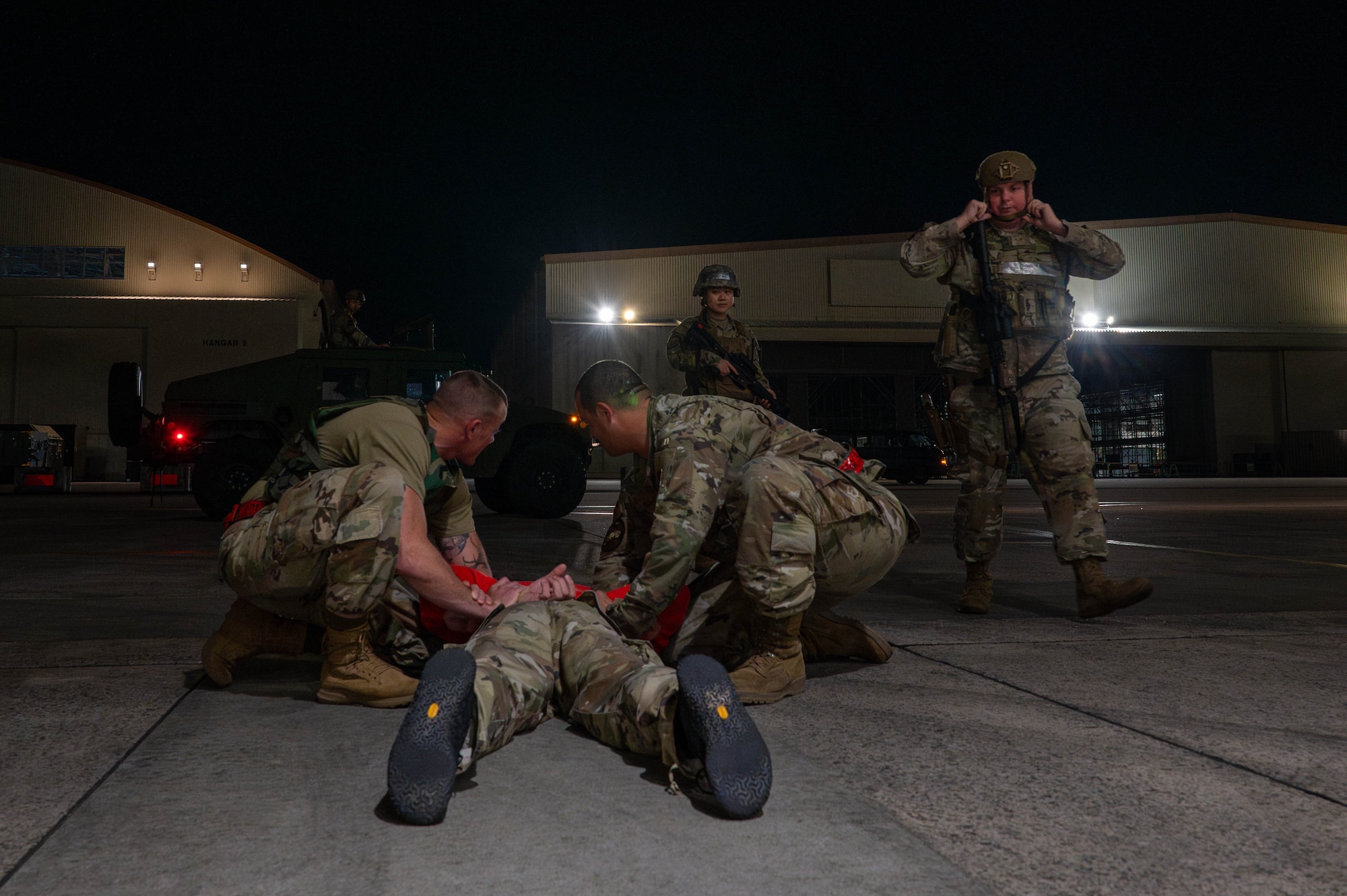 Two U.S. Air Force Airmen assigned to the 119th Expeditionary Fighter Generation Squadron detain a simulated intruder while awaiting the arrival of 18th Security Forces Squadron responders during base-wide operational readiness exercise, BH 26-1 at Kadena Air Base, Japan, Nov. 6, 2025. The scenario evaluated how quickly Airmen could identify, detain, and secure an intruder before security forces arrived on scene. (U.S. Air Force photo by Airman Nathaniel Jackson)