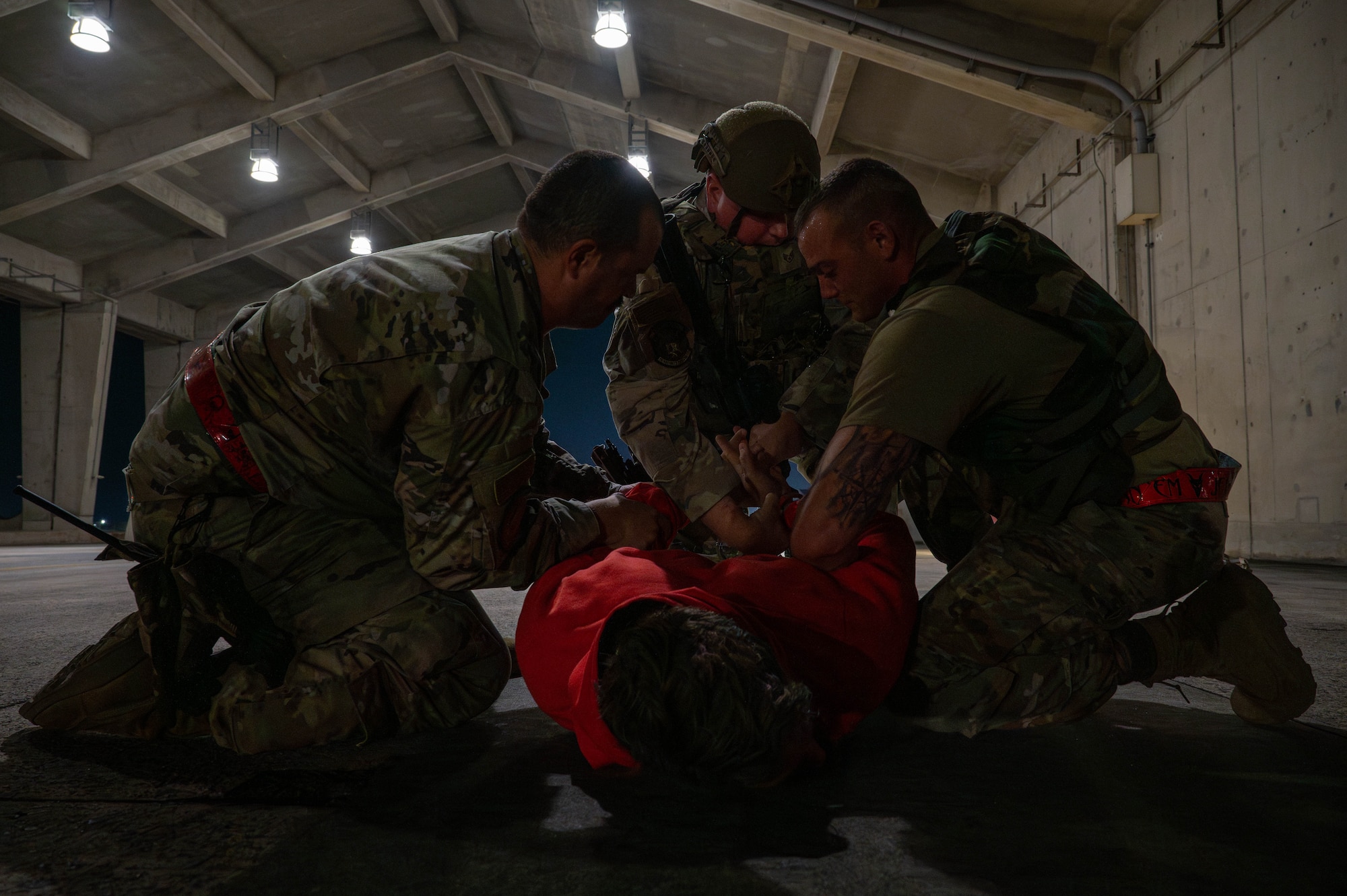Two U.S. Air Force Airmen assigned to the 119th Expeditionary Fighter Generation Squadron detain a simulated intruder as a U.S. Air Force Airman assigned to the 18th Security Forces Squadron arrives during base-wide operational readiness exercise, BH 26-1 at Kadena Air Base, Japan, Nov. 6, 2025. The scenario tested response time and coordination between maintainers and security forces during a simulated flightline intrusion. (U.S. Air Force photo by Airman Nathaniel Jackson)