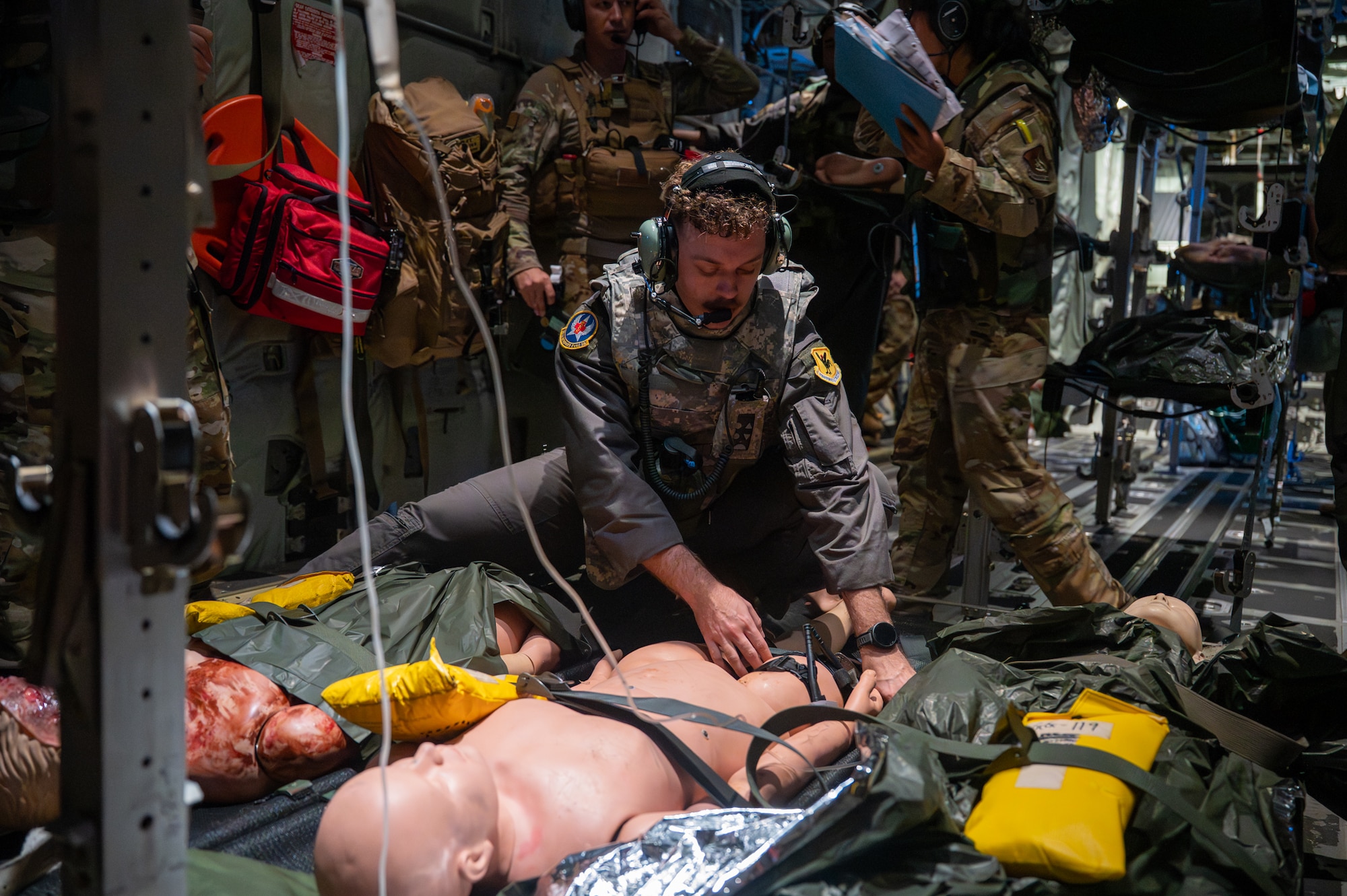 A service member simulates preforming patient care on a mannequin